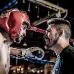 man in black talking to boxer inside ring