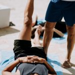 man lying on floor near man standing holding his leg