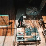 man standing beside brown wooden table