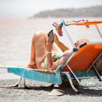 woman in white bikini lying on blue and white surfboard on beach during daytime